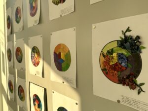 Multiple paper sheets of colourfull collages displayed on a wall. 