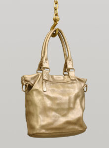Large bronze handbag hanging by a bronze chain.