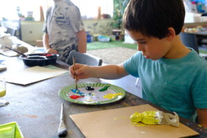 A child painting a handmade sculpture. 