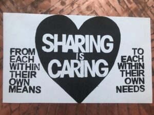 A black and white poster with text that says "Sharing is caring. From each within their own means, to each within their own needs".