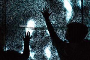 A dark panel of light with a pair of children's hands over the panel.