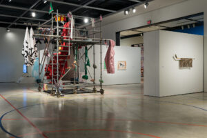 Hazel Mayer's installation, Muscle Panic, various sports equipment and items draped on square scaffolding in the middle of an art gallery